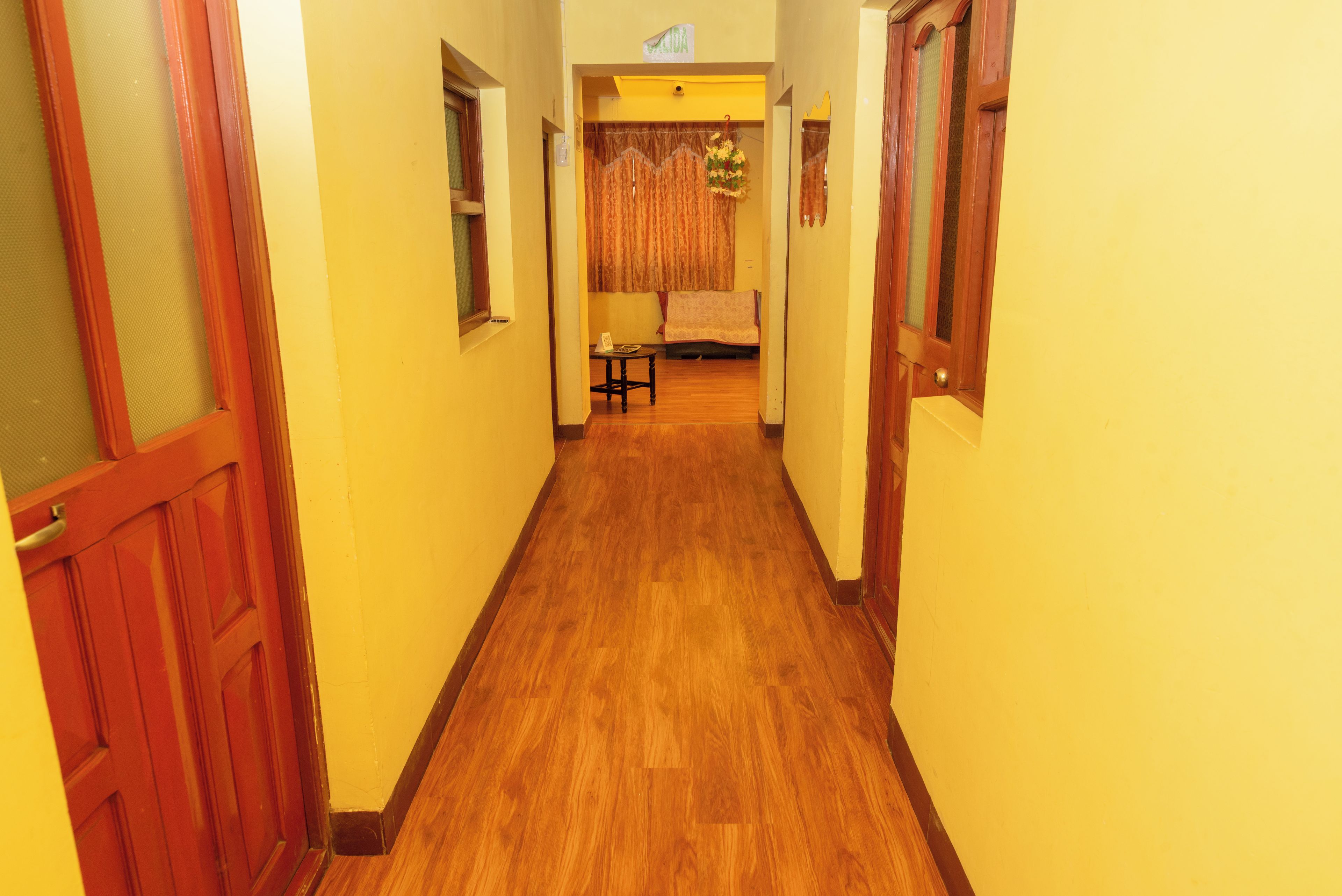 Un couloir au plancher de bois qui mène à une pièce contenant un lit et une table.