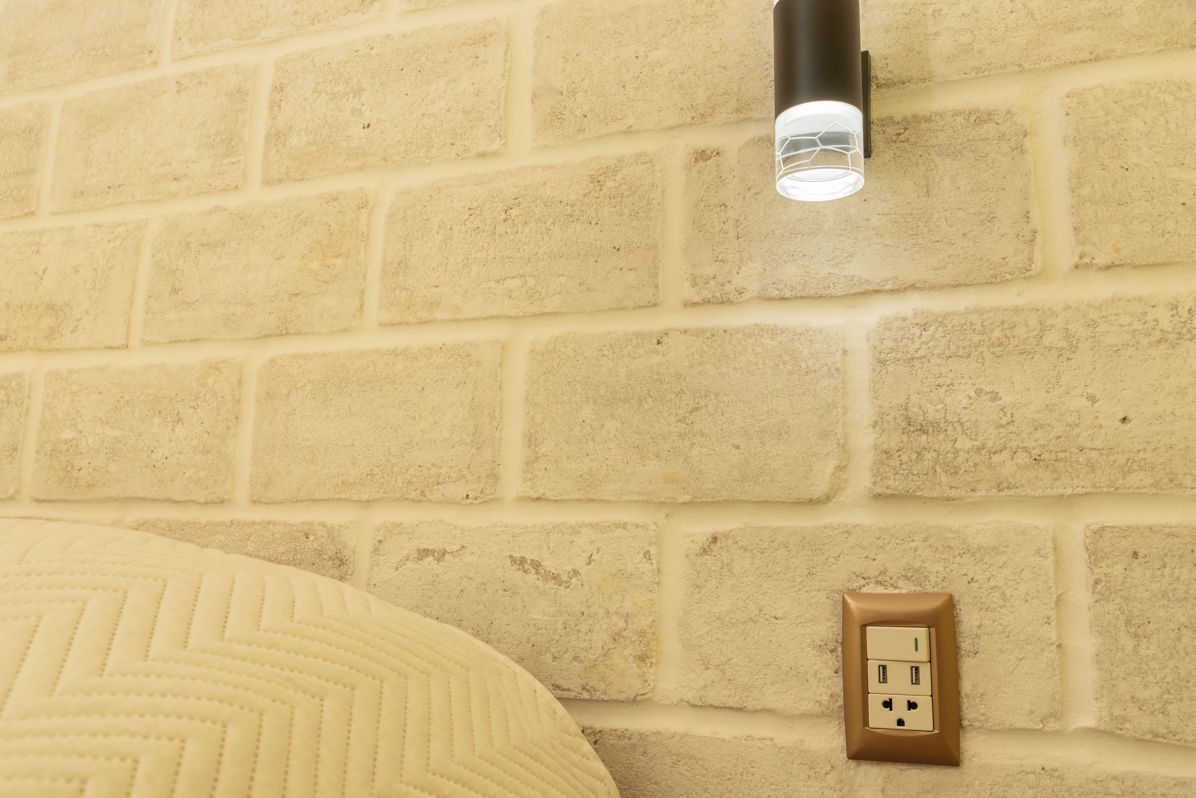 A brick wall with a light fixture and an electrical outlet.