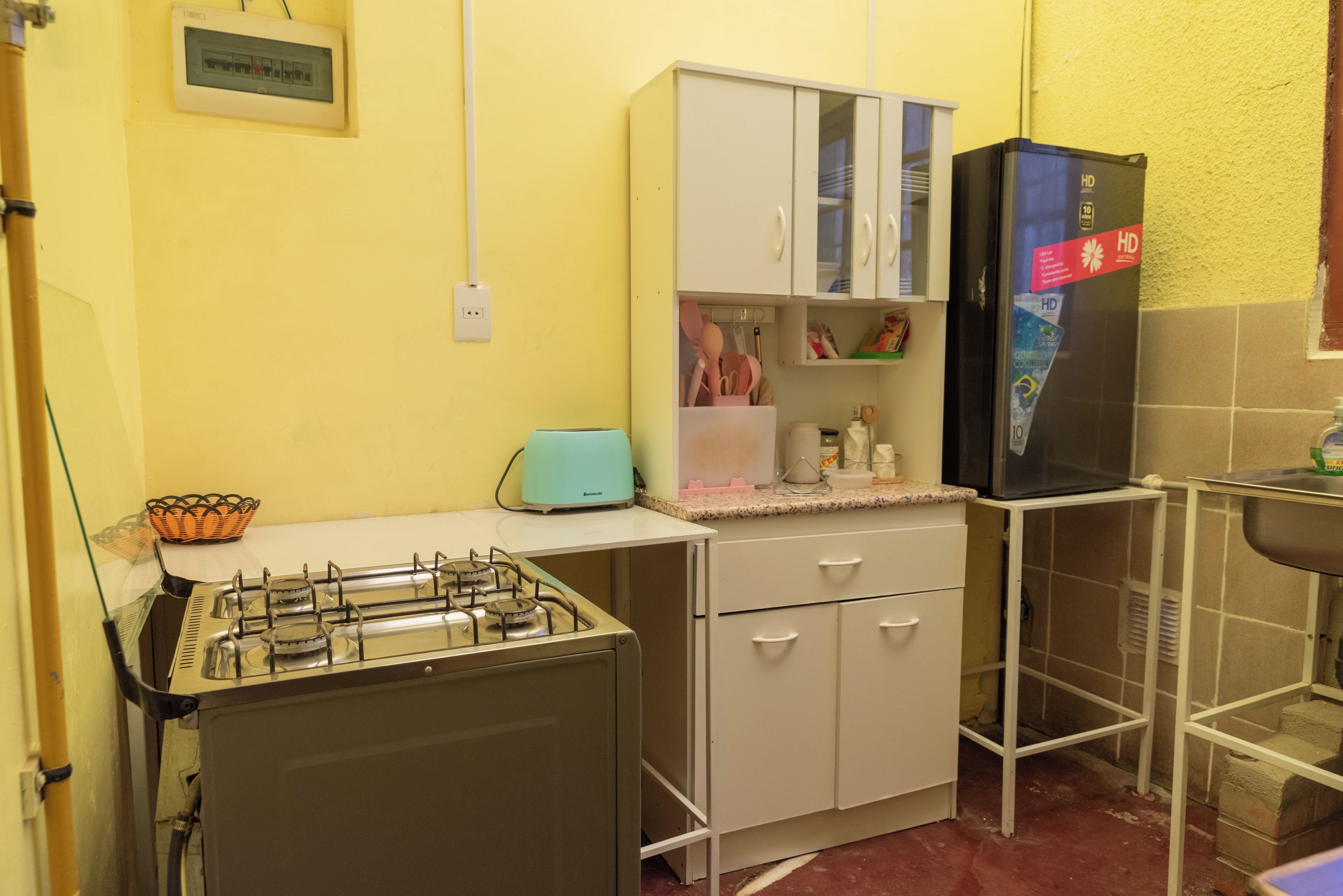 Cozinha compacta com fogão a gás, torradeira, geladeira e micro-ondas.