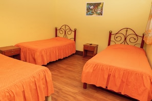 Een kamer met twee eenpersoonsbedden, een klein nachtkastje en een foto aan de muur.