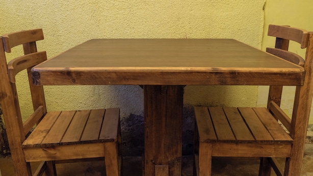 A wooden table with four chairs, set against a textured wall. - Alojamiento la Gran Estacion (Uyuni)