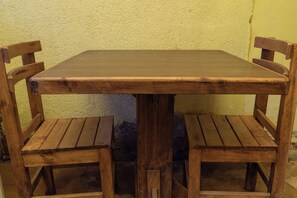 A wooden table with four chairs, set against a textured wall.