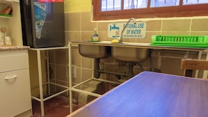 A compact kitchen with a refrigerator, sink, and a green dish rack. - Alojamiento la Gran Estacion (Uyuni)