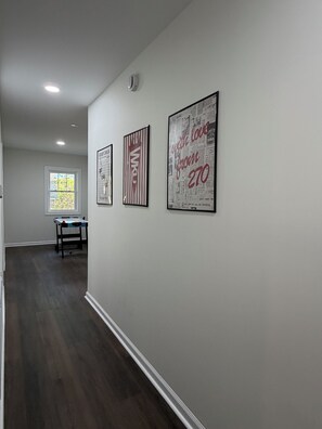 A hallway with a dining table and chairs, a window, and three framed posters on the wall.