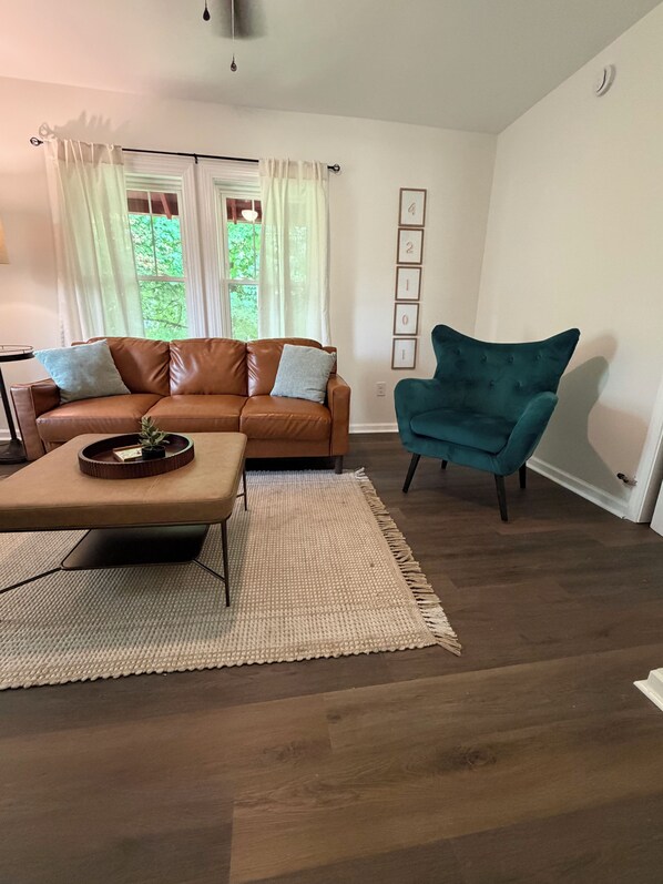 A living room with a brown leather sofa, a teal armchair, and a coffee table.