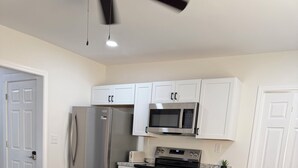Una cocina moderna con electrodomésticos de acero inoxidable, una mesa de comedor con mantel a cuadros y sillas azules y marrones.