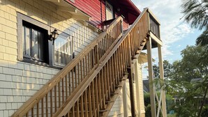 Una escalera de madera que conduce a una casa con techo rojo y fachada de ladrillo.