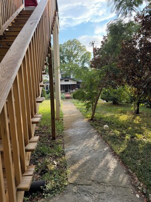 A wooden deck with a concrete pathway leading to a house.