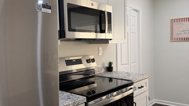 Una cocina moderna con electrodomésticos de acero inoxidable, microondas integrado y encimera de granito.