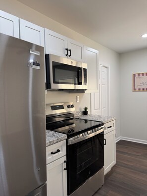 A modern kitchen with stainless steel appliances, a built-in microwave, and a granite countertop.