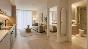 Moderni hotellihuone, jossa on pieni keittiö, sänky, kylpyhuone ja oleskelutila.