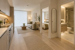 Habitación de hotel moderna con kitchenette, cama, baño y sala de estar.