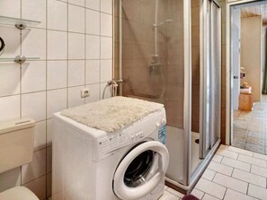 Un área de lavandería con lavadora, tendedero y ducha.