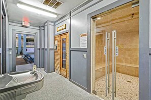 A public restroom with a sink, a wooden door, and a shower area. - Sun-Drenched Coastal Villa With Marsh Views (Hilton Head Island)
