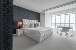 Ein modernes Schlafzimmer mit einem großen Bett, einem Schreibtisch und Blick durch ein großes Fenster.