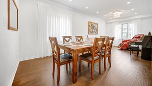 Uma área de refeições com mesa e cadeiras de madeira, uma poltrona de massagem e um quadro na parede.