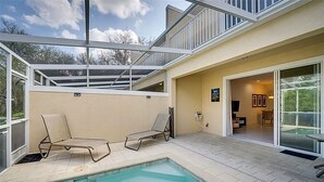 Uma área moderna da piscina ao ar livre, com duas espreguiçadeiras, um terraço envidraçado e vista para a paisagem circundante.