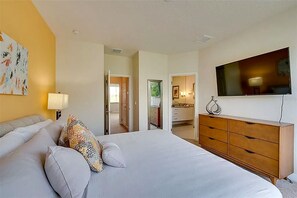 Ein Hotelzimmer mit einem Bett, einem Schminktisch, einem Fernseher und einem Gemälde an der Wand.