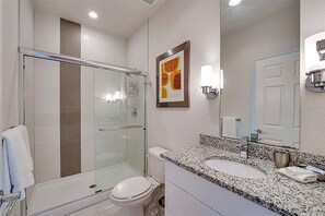 Ein modernes Badezimmer mit einer Duschkabine, einer weißen Toilette und einem Waschbecken mit Granitplatte.