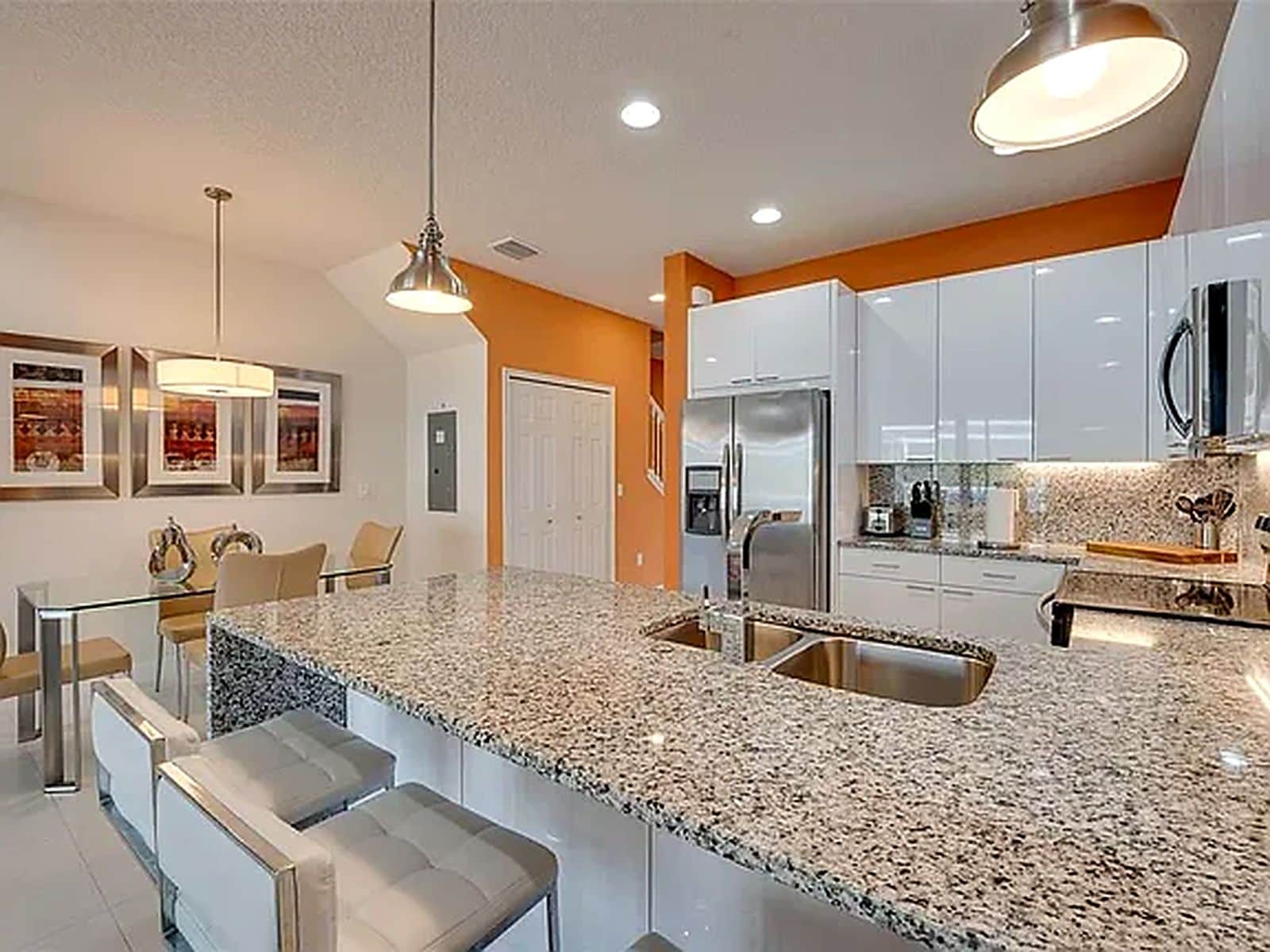 A modern kitchen with granite countertops, stainless steel appliances, and a dining area with bar stools.