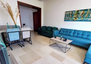 Sala de estar com um sofá azul, uma mesa de centro e um quadro na parede.