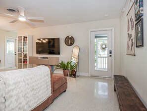 A bedroom with a bed, a TV, a clock, a mirror, and a door.
