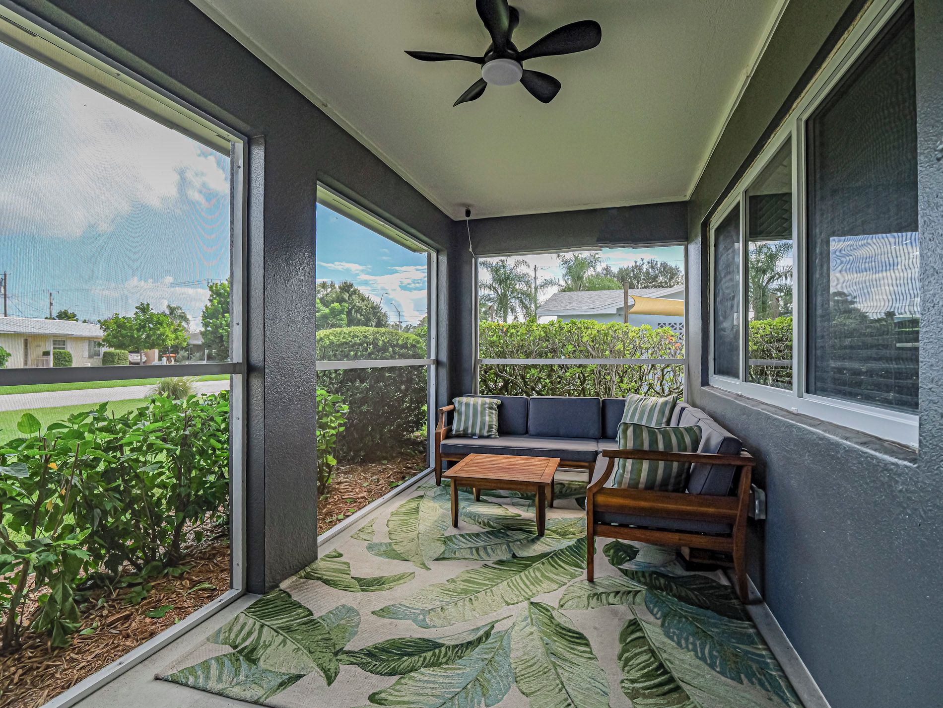 A covered porch with a ceiling fan, a sofa with cushions, and a coffee table.