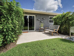 A modern house with a patio, a bench, and a potted plant.