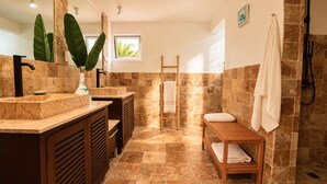 A bathroom with a large mirror, two sinks, a wooden bench, and a towel rack. - Villa Punta Espada CapCana, 6-bedroom, with pool and hole 8 (Punta Cana)