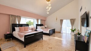 A bedroom with two beds, a flat-screen TV, a painting, and a ceiling light fixture. - Villa Punta Espada CapCana, 6-bedroom, with pool and hole 8 (Punta Cana)