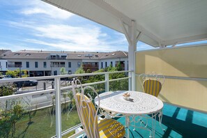 A balcony with a table and chairs, overlooking a residential area with houses and parked cars. - Bed and Breakfast 'Chambre Jane - Chez Claudine' with Balcony and Wi-Fi (Le Teich)