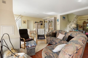 A living room with a sofa, chairs, a small table, and a bookshelf. - Bed and Breakfast 'Chambre Christy - Chez Claudine' with Balcony and Wi-Fi (Le Teich)
