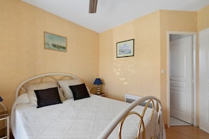 A bedroom with a bed, two wall-mounted paintings, a bedside lamp, and a door. - Bed and Breakfast 'Chambre Christy - Chez Claudine' with Balcony and Wi-Fi (Le Teich)