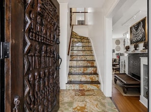 A spiral staircase with a patterned floor leading to a landing area. - Luangisa African House (Mount Vernon)