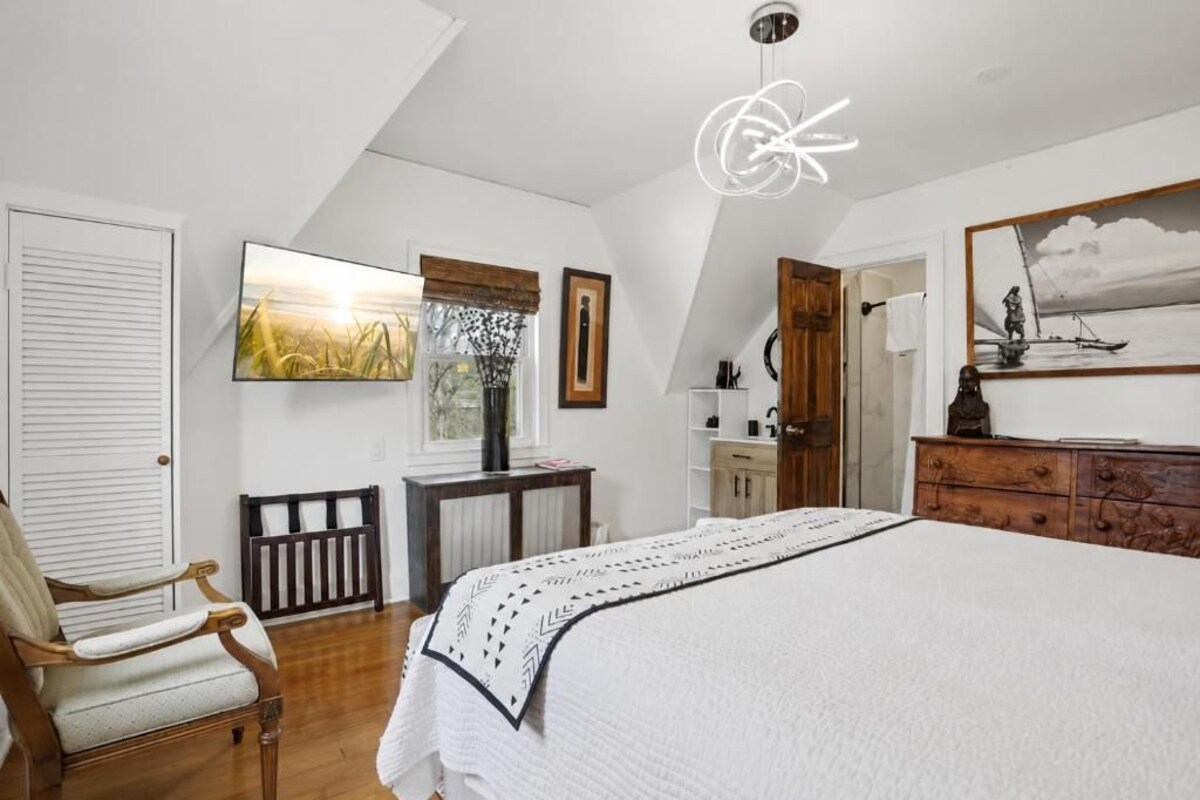 Ein Schlafzimmer mit einem großen Bett, einem Holzstuhl, einem Schreibtisch und einer Heizung.