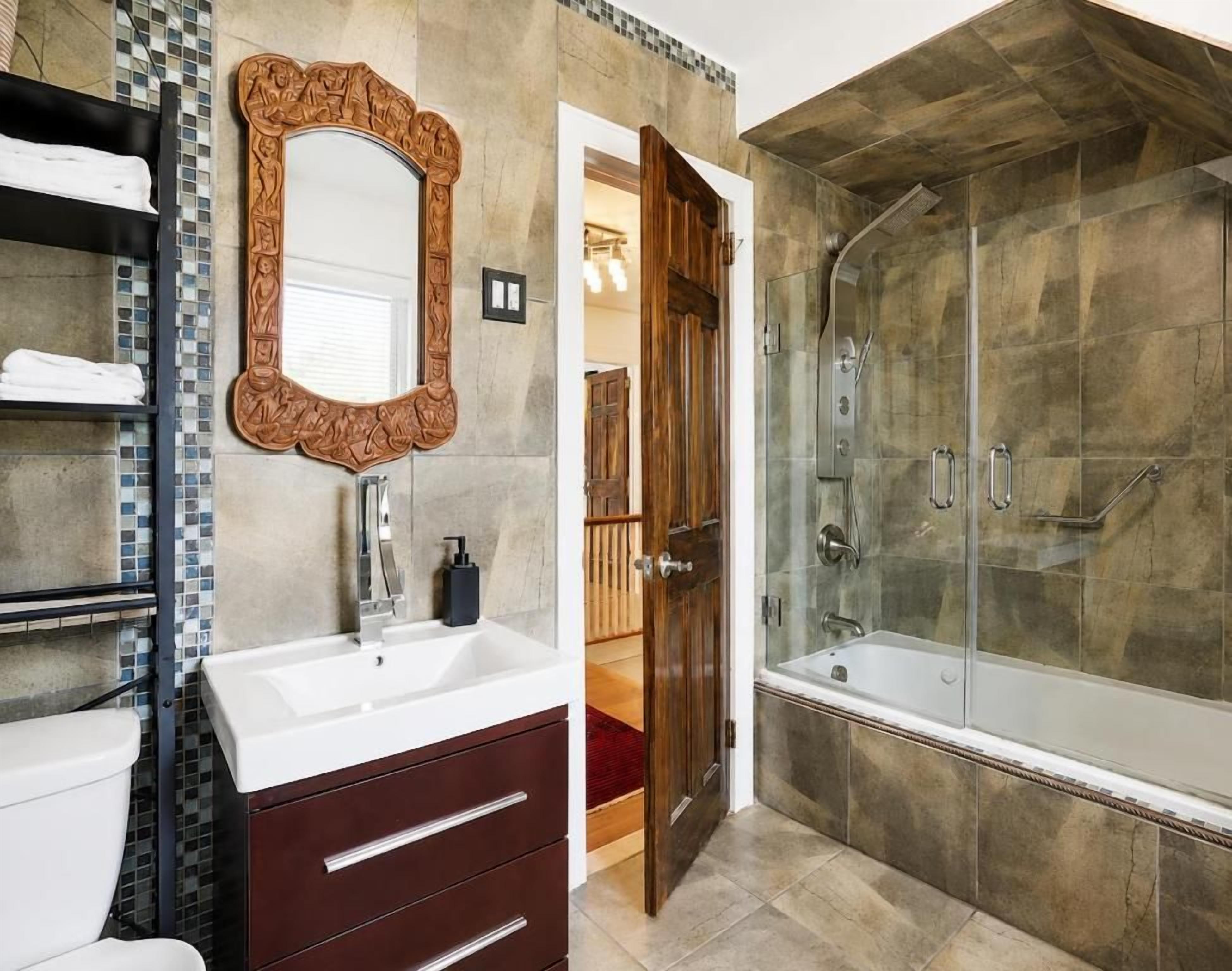 A bathroom with a large mirror, a bathtub, and a shower.