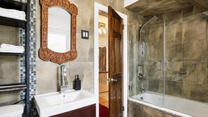 Ein Badezimmer mit großem Spiegel, einer Badewanne und einer Dusche.