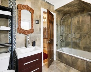 A bathroom with a large mirror, a bathtub, and a shower. - Luangisa African House (Mount Vernon)