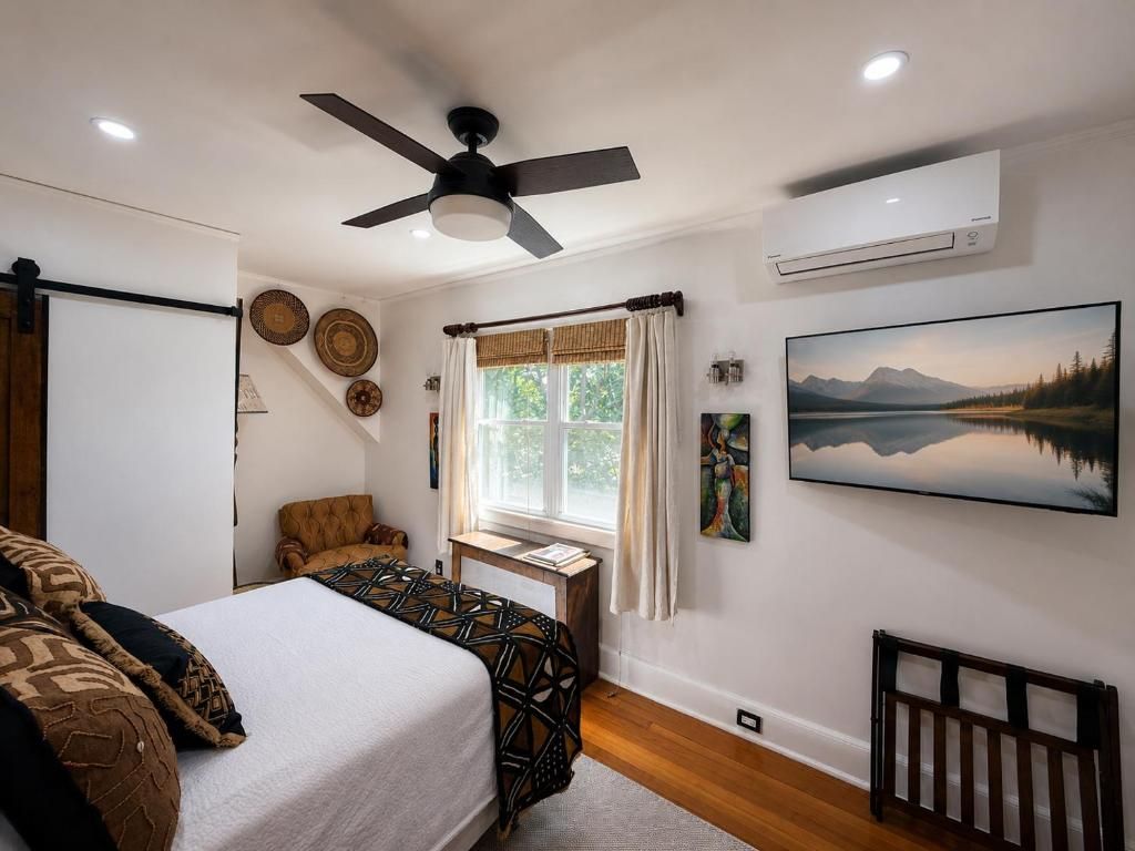 A bedroom with a bed, a chair, a desk, and a window with curtains.