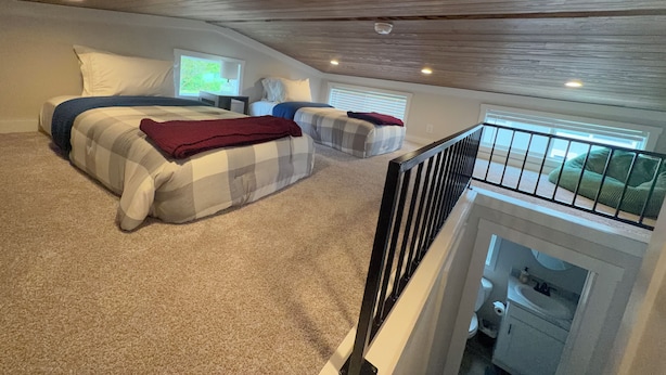 Una camera da letto con due letti, una finestra, un balcone e una scala.