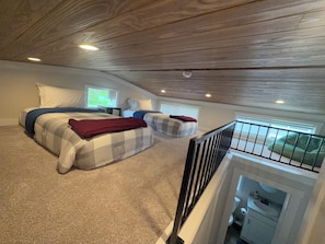 Un dormitorio con dos camas, una ventana, un balcón y una escalera.