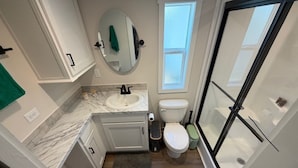 Un bagno con un WC bianco, un lavandino, uno specchio e una finestra.