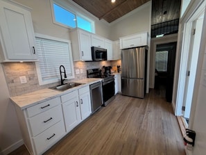 A kitchen with white cabinets, a stainless steel refrigerator, a microwave, and a sink. - Magnolia MS Riverbend (Vicksburg)