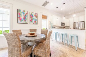 A modern kitchen with white cabinetry, stainless steel appliances, and a central island with bar stools. - Resort Bungalo with Golf Cart & Beach Access (Miramar Beach)