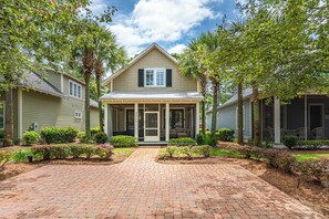 A two-story house with a covered porch, brick driveway, and well-maintained landscaping. - Resort Bungalo with Golf Cart & Beach Access (Miramar Beach)