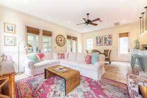 A spacious living room with a white sectional sofa, a wooden coffee table, and a colorful rug. - Resort Bungalo with Golf Cart & Beach Access (Miramar Beach)