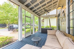A covered outdoor seating area with a ceiling fan, a table, and a sofa. - Resort Bungalo with Golf Cart & Beach Access (Miramar Beach)