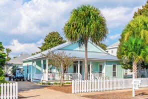 A single-story house with a blue roof and white picket fence. - Beach Cottage with Golf Cart & Community Pool (Destin)