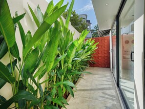 Um edifício moderno com porta de vidro, parede de tijolos vermelhos e plantas verdes exuberantes.
