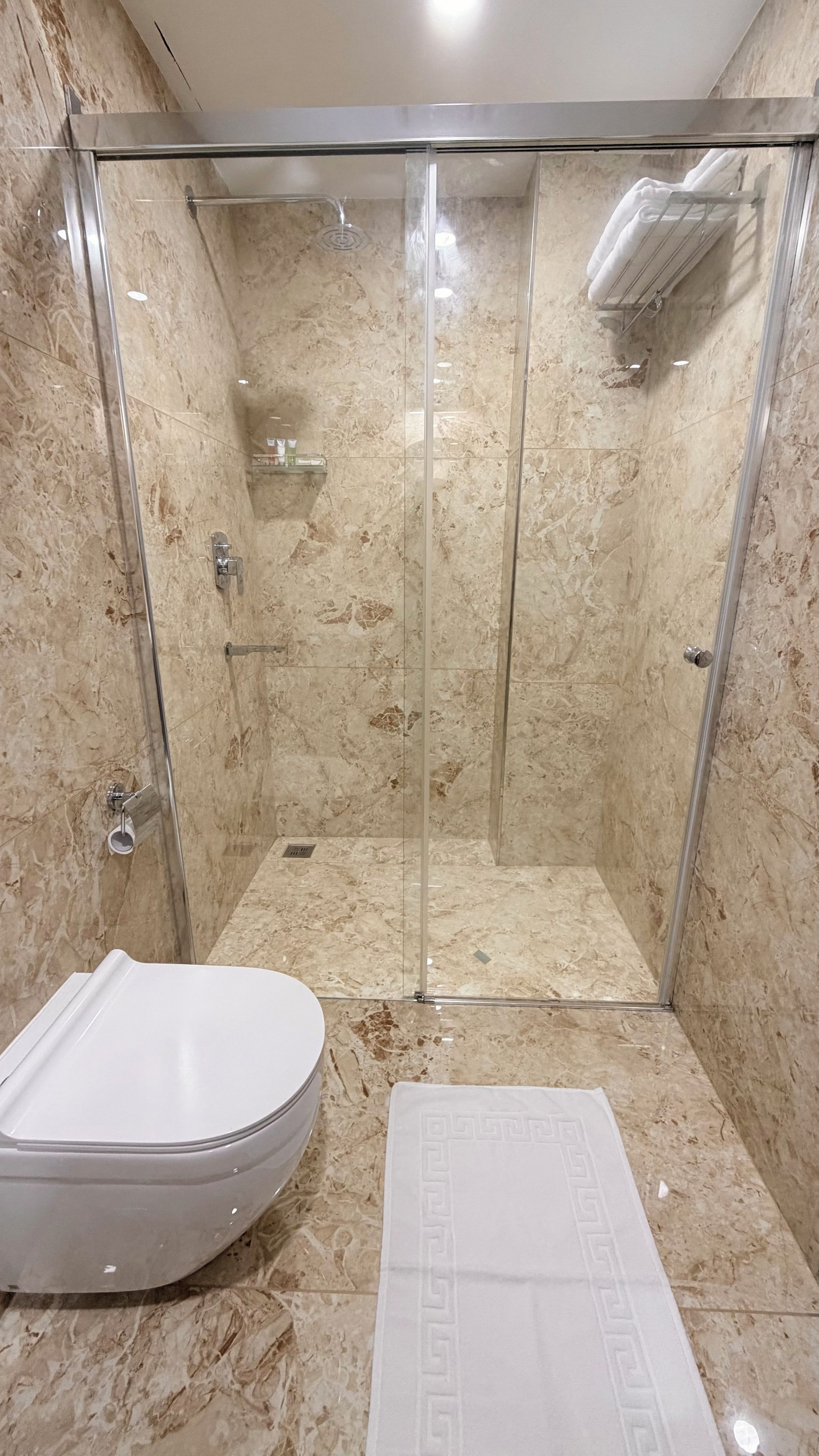 Een badkamer met een douchecabine, een toilet en een handdoek op de vloer.